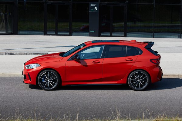 Red hatchback parked on a forecourt in front of a glass building